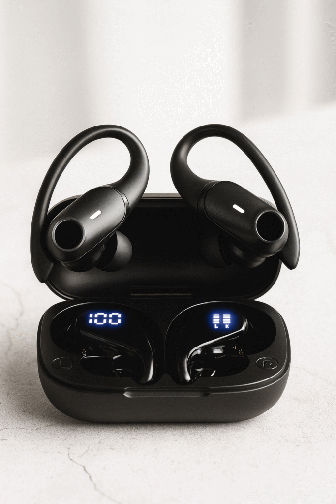 Matte black wireless earbuds with ear hooks placed inside an open charging case, featuring blue LED battery indicators and styled on a clean, light-toned surface for a professional photoshoot look